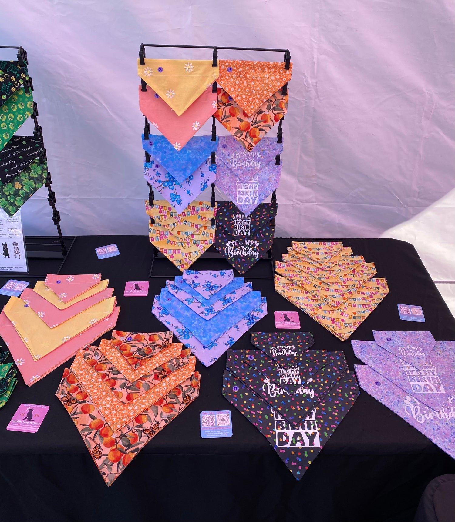 18 dog biscuits are placed in three rows of six on a white surface. The dog biscuits are all cut in the shape of the state of Arizona. Six of the biscuits have a desert motif stamped into them. The biscuits are placed randomly with the flavors of biscuits ranging from Broccoli and Peas, Sweet potato and Carrots, Pumpkin, and Peanut butter and Banana.