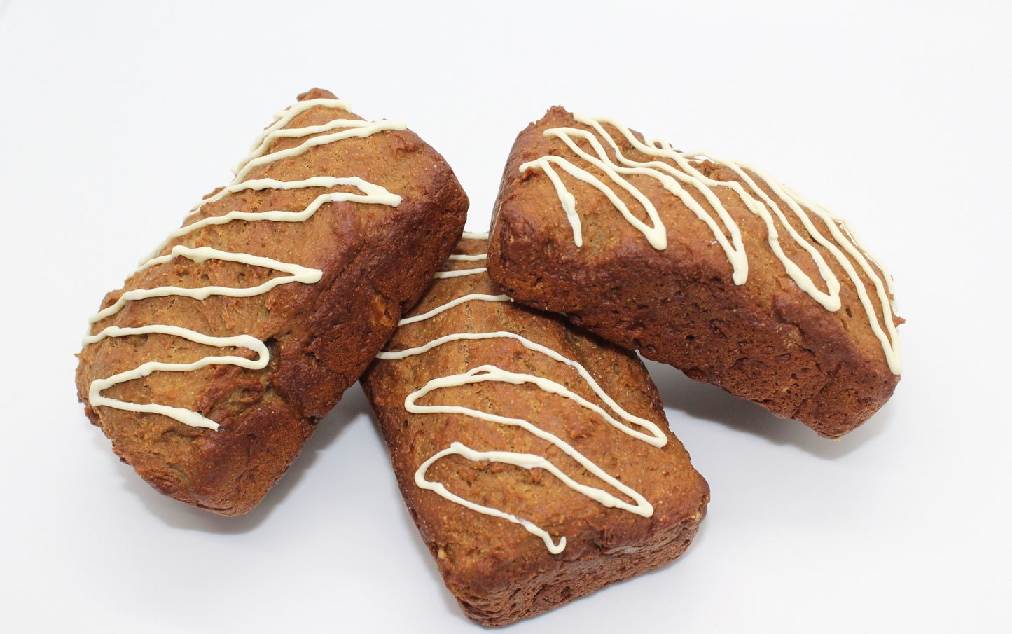 Three stunning peanut butter and banana flavored bakery loaves topped with a white frosting drizzle displayed in a stacked pattern.
