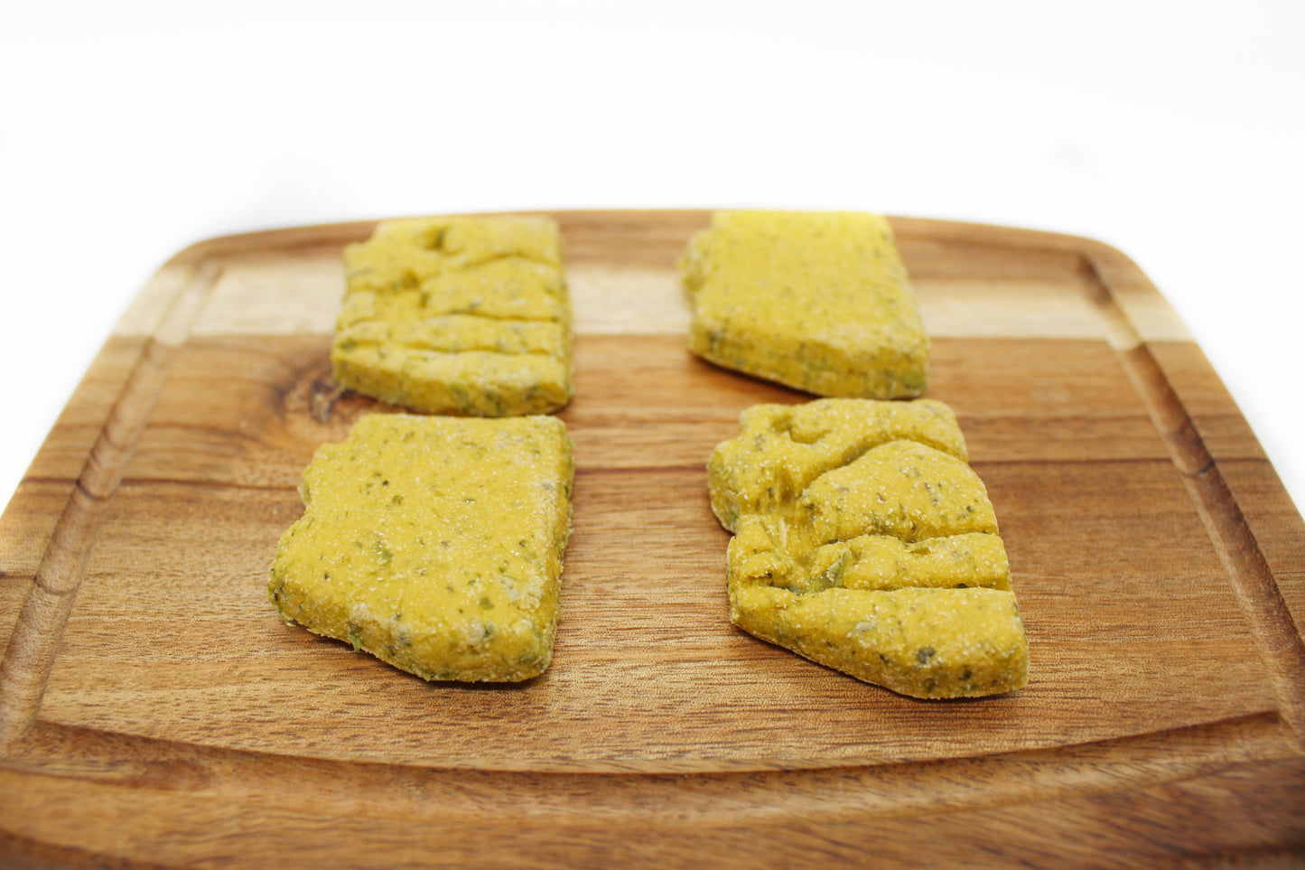 Four Arizona shaped dog treats taken from a side view. Flecks of Cilantro and Parsley can be seen in the treats.
