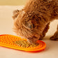 A tiny dog licks peanut butter off the oval lick mat.