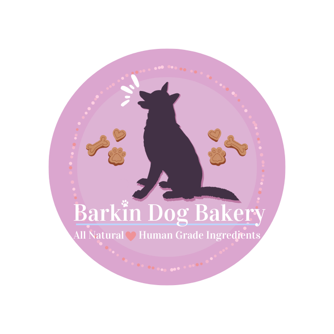 Barkin Dog Bakery Logo. Subtitle, All natural human grade ingredients. Picture shows dark purple barking German Shepherd surrounded by delicious dog treats.