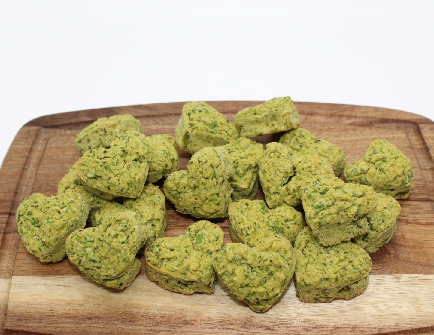 A bunch of green heart-shaped Broccoli and Peas training treats on a cutting board.