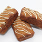 Three stunning peanut butter and banana flavored bakery loaves topped with a white frosting drizzle displayed in a stacked pattern.