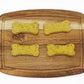four green bone shaped dog treats on a cutting board in two rows.
