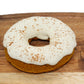 A tasty white frosted pumpkin dog donut sprinkled with cinnamon.