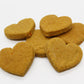 Six sweet potato and carrot flavored dog biscuits all cut in a heart shape. 