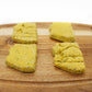Four Arizona shaped dog treats taken from a side view. Flecks of Cilantro and Parsley can be seen in the treats.  