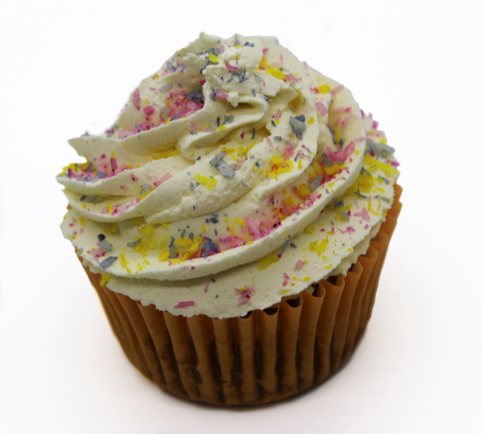 A funfetti cupcake wrapped in a orange paper liner, piped with white frosting and topped with rainbow coconut flakes. The rainbow coconut flakes are in pink, yellow, and blue.