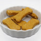 Six sweet potato and carrot flavored dog bisciuts in a small bone shape displayed in a small white dish.