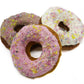 Three Frosted dog donuts with rainbow coconut flakes. Dog donuts are frosted in pink, white, and carob. 