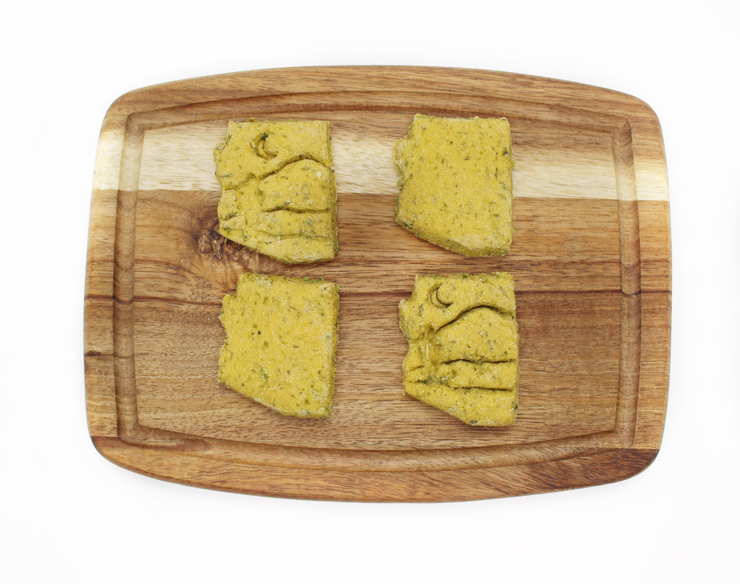 Delicious Broccoli and Peas based dog treat. Four green treats  sit on a cutting board.  All treats are cut in the shape of the State of Arizona, two have a desert theme stamped into them.