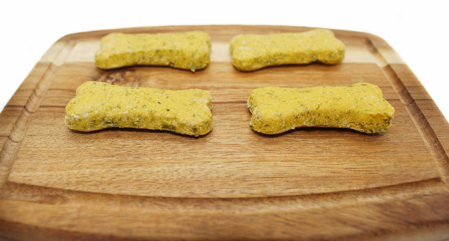 Four green bone shaped dog treats on a cutting board in two rows.