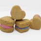 Four apple and banana heart shaped whoopies with dog safe icing in the middle. Three of the whoopies have pink icing in the middle and one has blue icing.